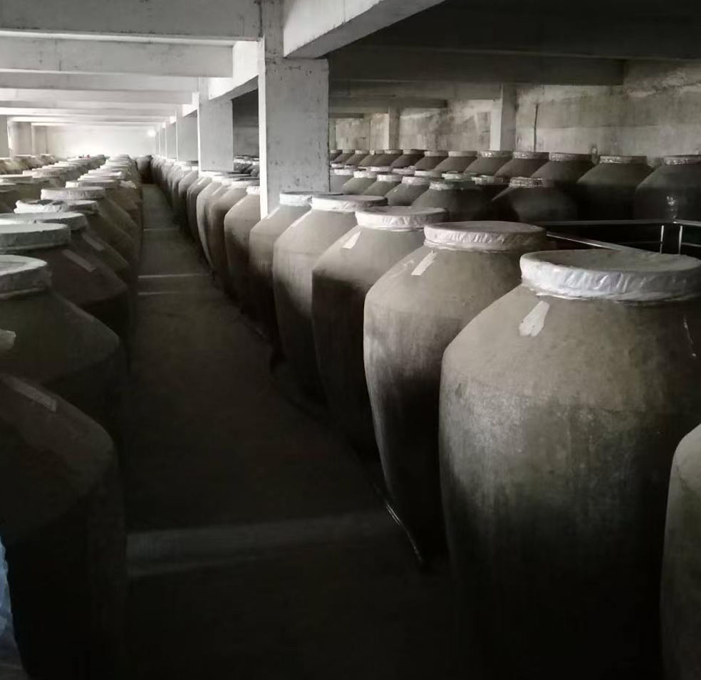 现代化酿酒厂房外观,红砖建筑,传统屋顶设计,厂区绿树成荫,阳光洒在建筑物上,展现专业酿酒环境